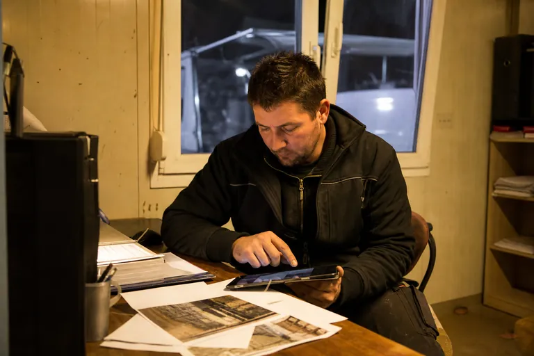 Bauleiter prüft am Abend im Baucontainer einen Tagesbericht auf einem Tablet